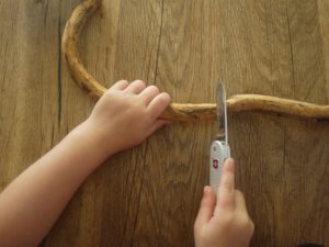 Kinder werken mit dem Taschenmesser einen Wurzeldrachen. Als erstes weg mit der Rinde. Foto (c) kinderoutdoor.de